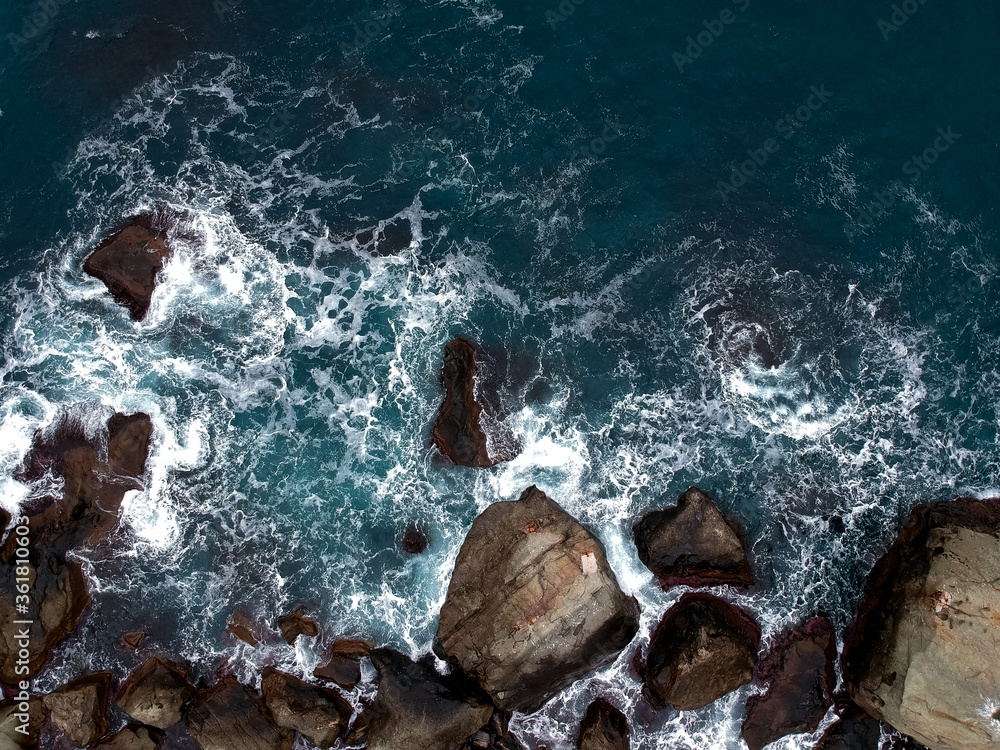 View from the height of the waves breaking on the rocks and white foam