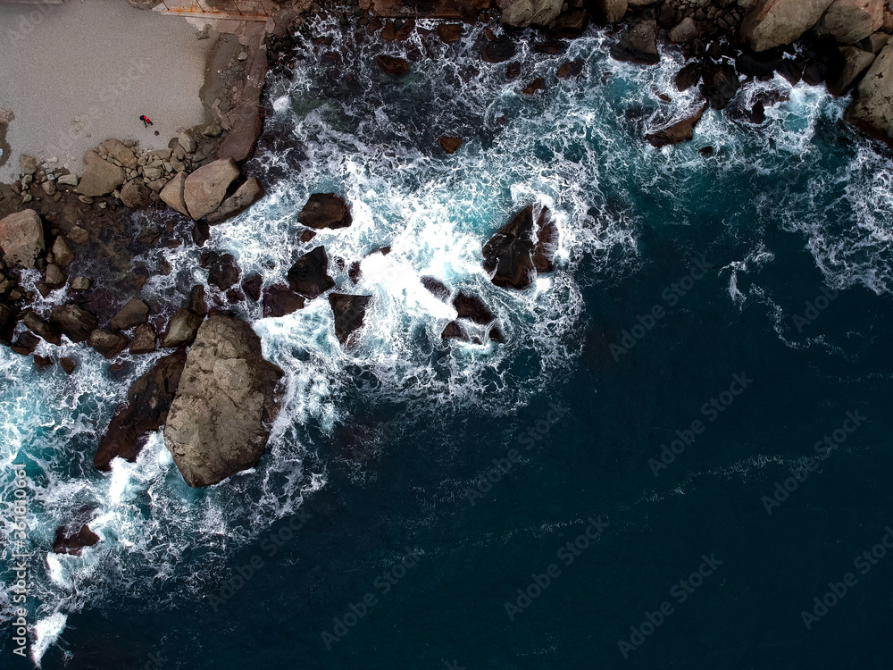 View from the height of the waves breaking on the rocks and white foam