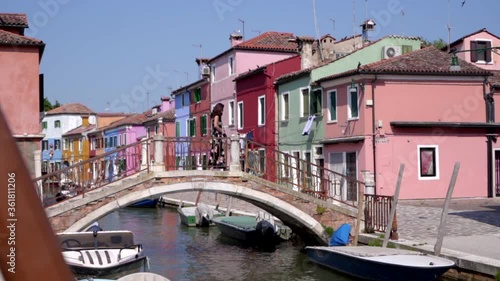 Wallpaper Mural Young attractive woman walking on a bridge surrounded by colorful buildings meanwhile the boats float in the canal. Venice Burano Italy Torontodigital.ca