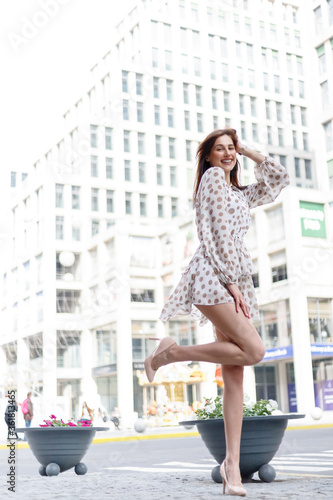 Young attractive pensive woman beautiful dress thoughtfully looking in camera standing on cozy city street