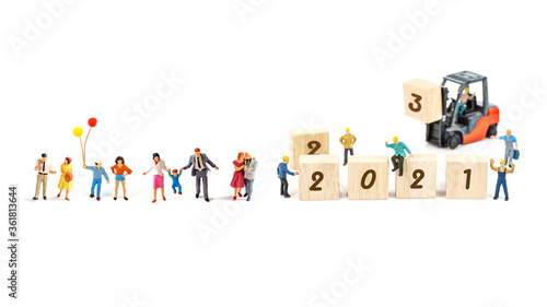 miniature worker team building standing front of forklift machine with   2021 number on wooden block on white background decoration to Happy new year 2021 concept.