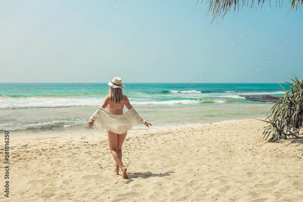 Happy traveller woman in white enjoys her tropical beach vacation in sunny day. Holidays, Travel, Coastline, Freedom concept. Happy traveller woman in white enjoys her tropical beach vacation in sunny day. Holidays, Travel, Coastline, Freedom concept.