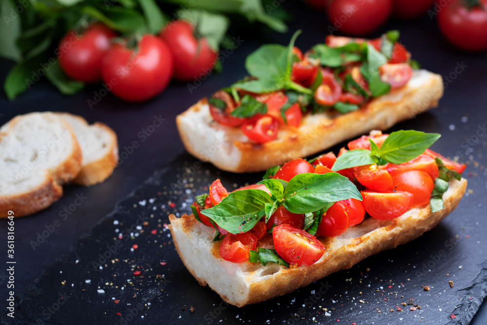 Homemade bruschetta with cherry tomatoes and basil closeup on a slate board. Italian cuisine. Antipasti. Vegan food