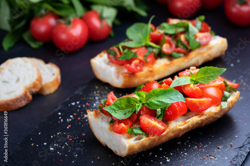 Homemade bruschetta with cherry tomatoes and basil closeup on a slate board. Italian cuisine. Antipasti. Vegan food