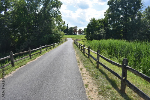Scenic footpath and bicycle trail at Thompson Park in Holmde, New Jersey, USA, on a mostly sunny day with puffy cumulus clouds