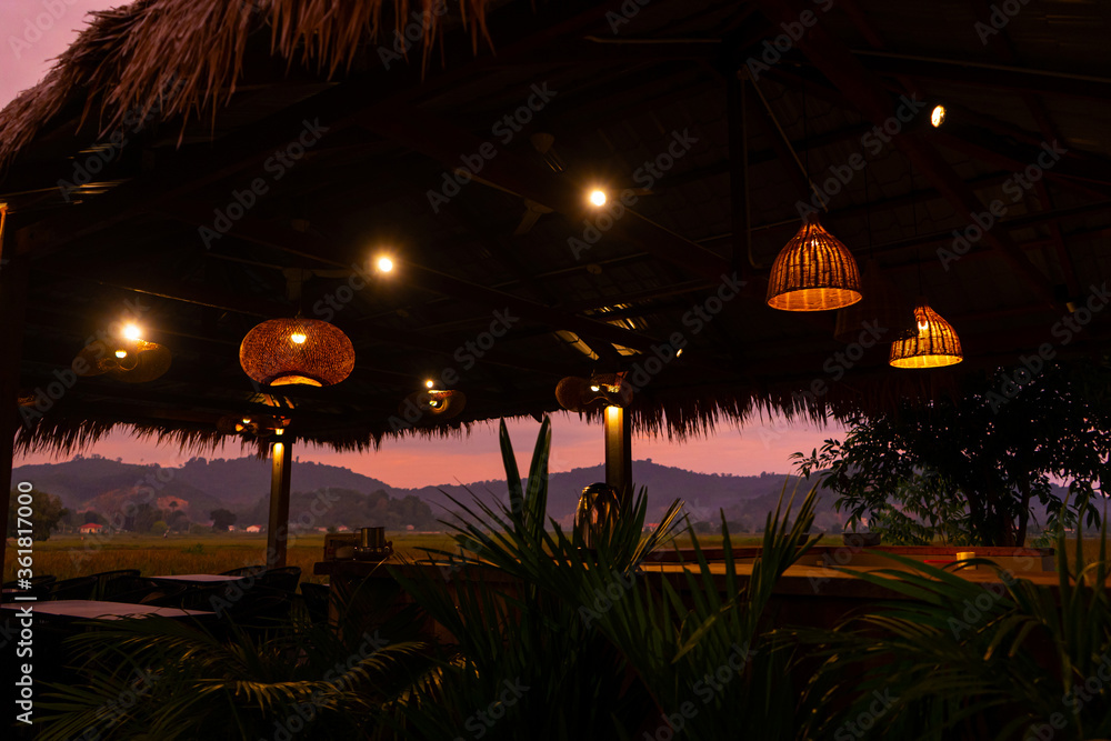Beautiful pink sunset in the tropics. Street canopy from hay, kitchen area with rice field view