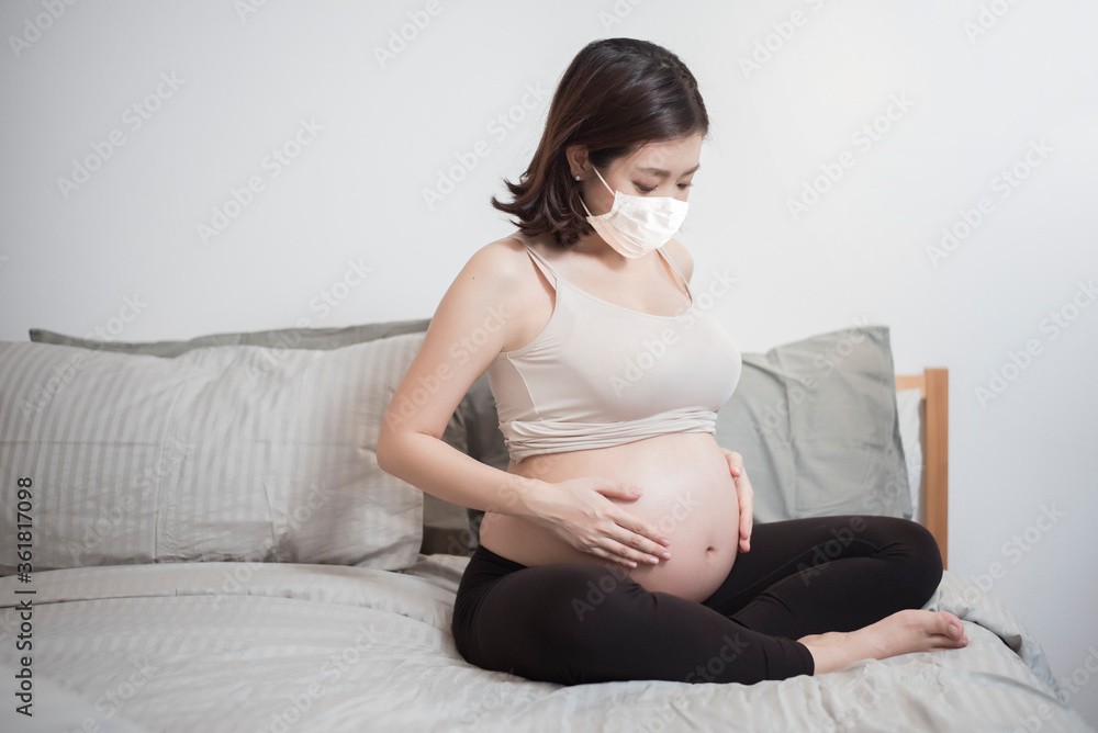 Beautiful asian pregnant woman is wearing protective mask in her home , Coronavirus protection concept Beautiful asian pregnant woman is wearing protective mask in her home , Coronavirus protection concept