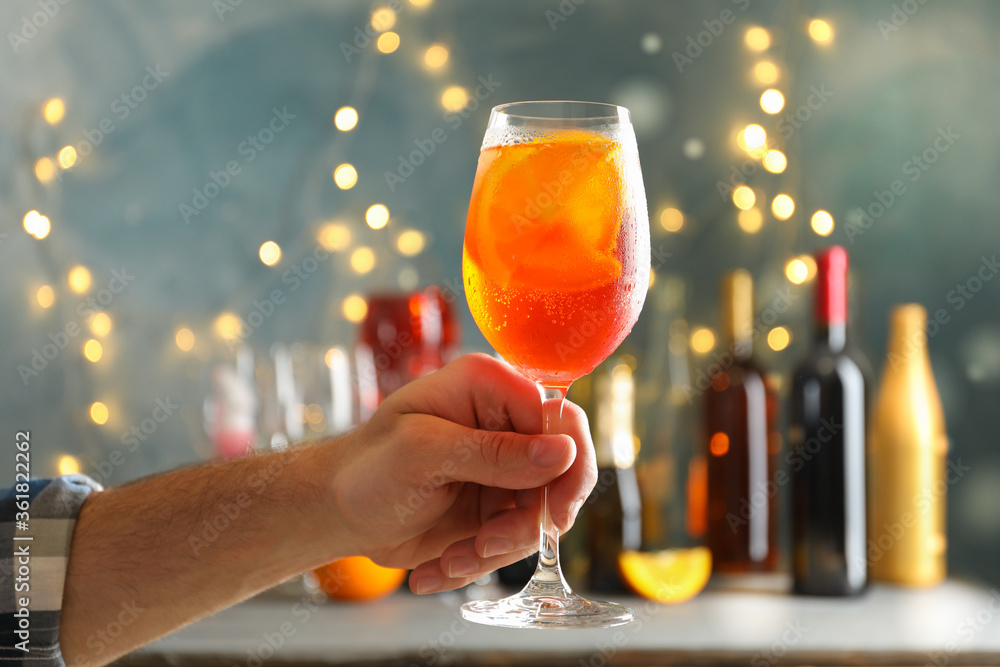 Male hand holds glass of aperol spritz. Making summer cocktail