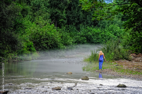 Girl crosses a forest river