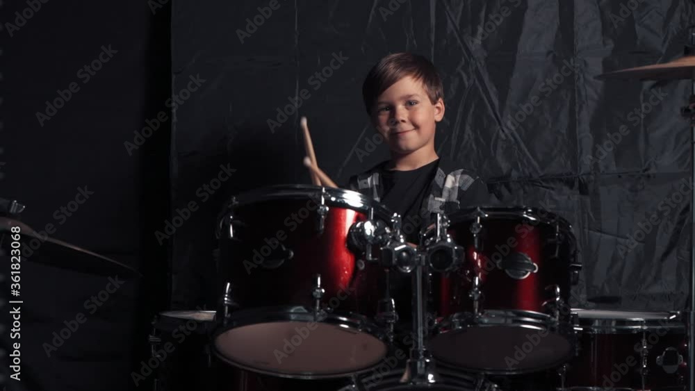 A contented boy hits the drums with drumsticks. Rehearsal before the concert. A contented boy hits the drums with drumsticks. Rehearsal before the concert.
