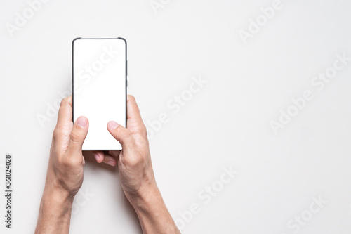 Man uses mobile smart phone with isolated blank white screen. Mockup with copy space.