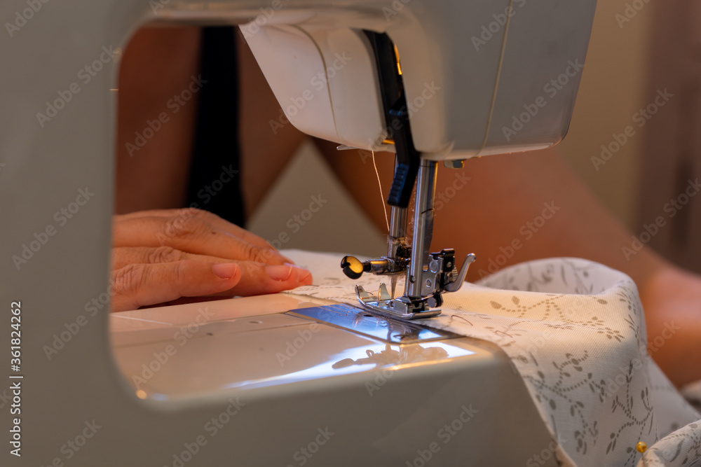 Detail of a woman's hands working with the sewing machine at home