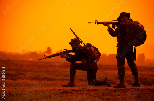 Team special forces. soldier assault rifle with silencer.Silhouette action soldiers hold weapons.military and danger concept.