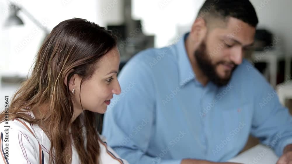 Creative colleagues sitting at workplace together, talking, discussing project. Day, static shot, side view. Teamwork or brainstorm concept Creative colleagues sitting at workplace together, talking, discussing project. Day, static shot, side view. Teamwork or brainstorm concept