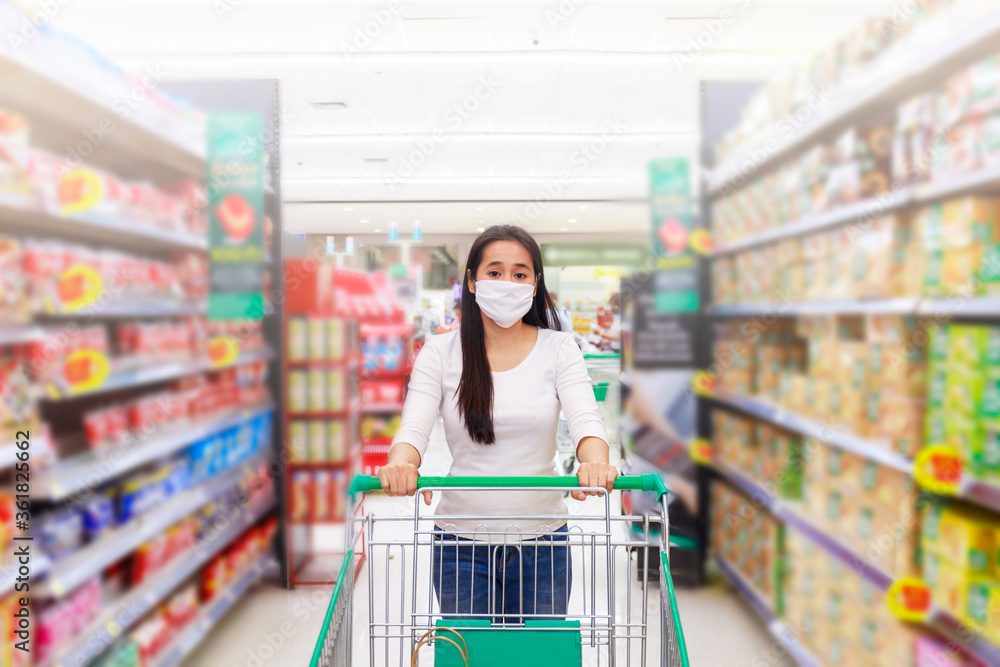 Asian woman wear face mask push shopping cart in supermarket department store. Girl looking grocery to buy something. During coronavirus crisis or covid19 outbreak. Women wearing protective face mask Asian woman wear face mask push shopping cart in supermarket department store. Girl looking grocery to buy something. During coronavirus crisis or covid19 outbreak. Women wearing protective face mask