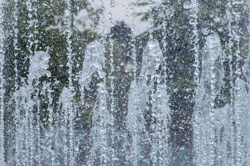 Splashes of water against the green background. Water sprays in sunny day close-up.