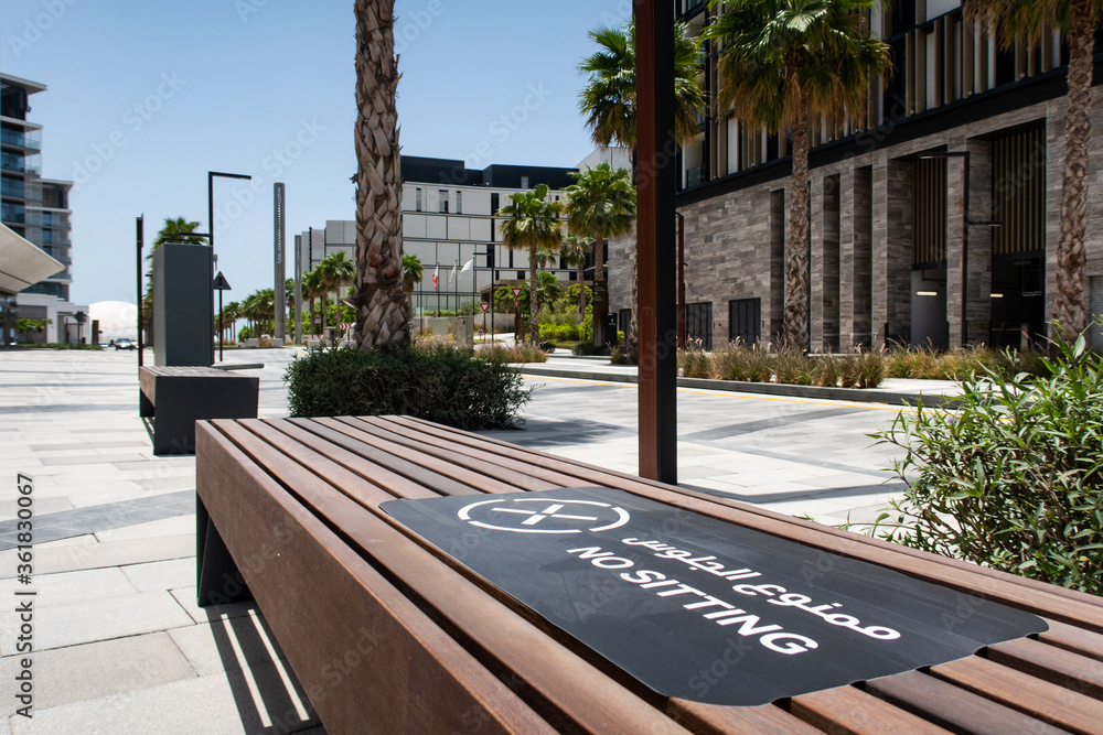 DUBAI, UAE. Brown wooden bench forbidden to sit with NO SITTING sign in