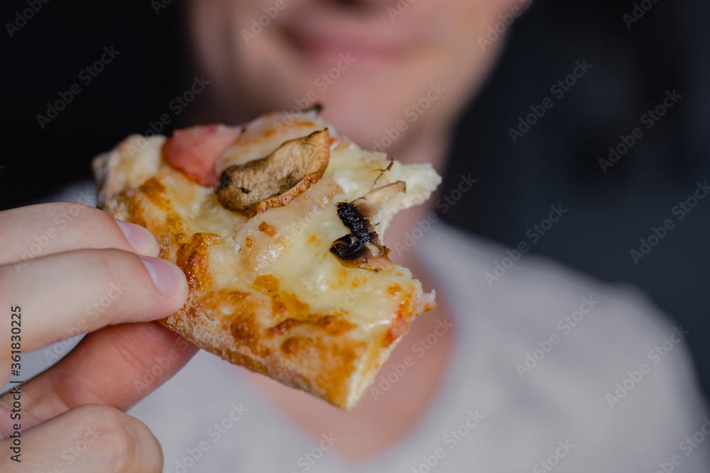 Close up portrait of excited happy hungry young man eating a piece of pizza, focus pizza. Young caucasian man eating pizza Close up portrait of excited happy hungry young man eating a piece of pizza, focus pizza. Young caucasian man eating pizza