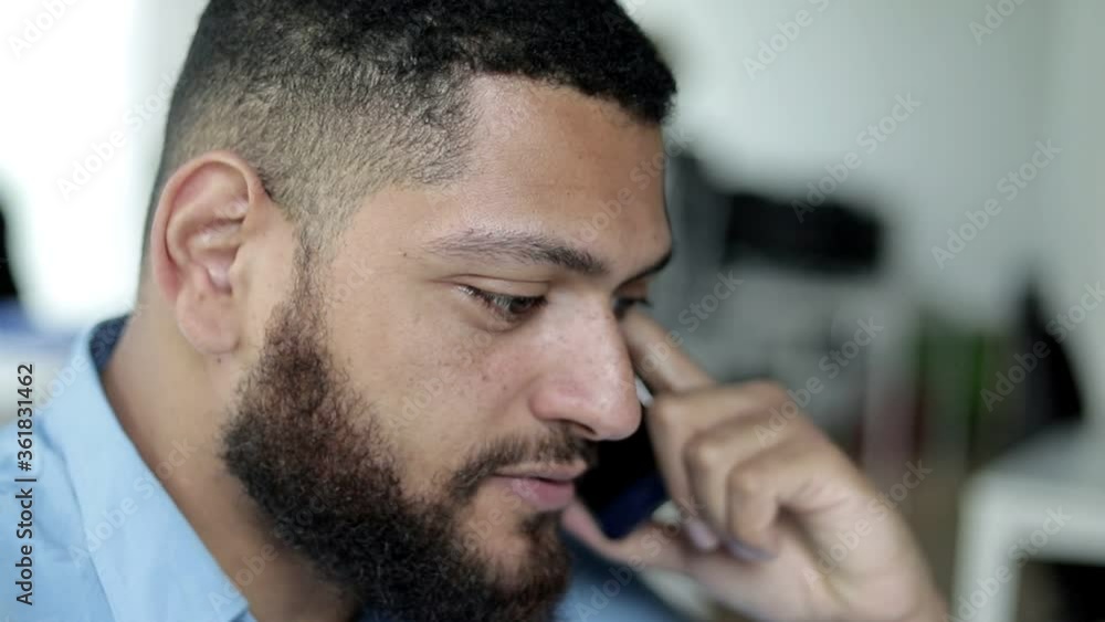 Serious handsome employee speaking on mobile phone at workplace in office or co-working space. Side view, closeup shot. Corporate communication concept Serious handsome employee speaking on mobile phone at workplace in office or co-working space. Side view, closeup shot. Corporate communication concept