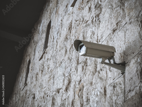 The surveillance camera is mounted on a wall with narrow windows and rough masonry.