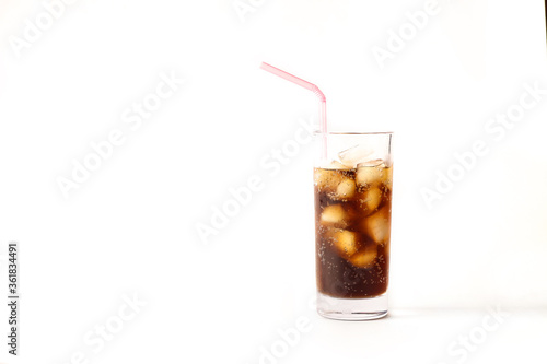 Refreshing glass of cool cola with ice and straw on a white background