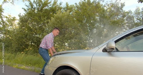 Caucasian man opens the hood of broken smoking car that overheated. emergency light, engine problem, worried. Car accident. Car trouble. medium shot slow motion