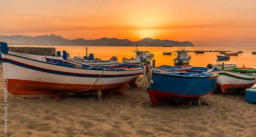 Naklejka premium A close up of colourful fishing boats at Aspra Sicily as the sun sets over the Gulf of Palermo on a summer's evening