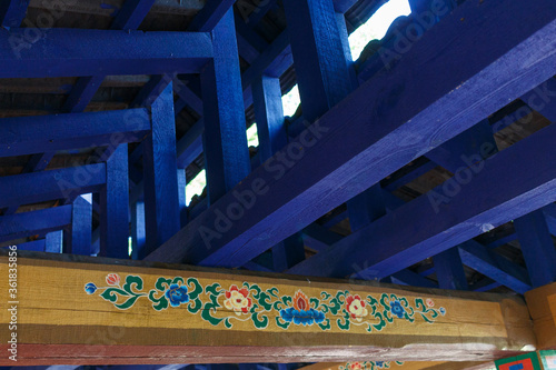 Blue wooden beams under the roof of a Tibetan arbor. Wooden floors with a Tibetan pattern.