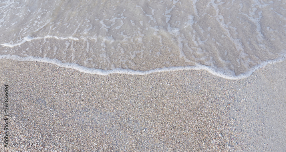Close-up of white sand, washed by soft sea waves