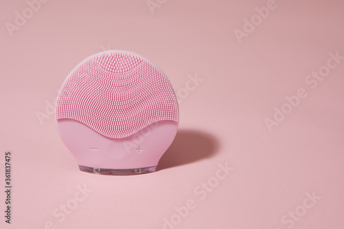 Silicone electric facial cleanser brush for skin care on pink background