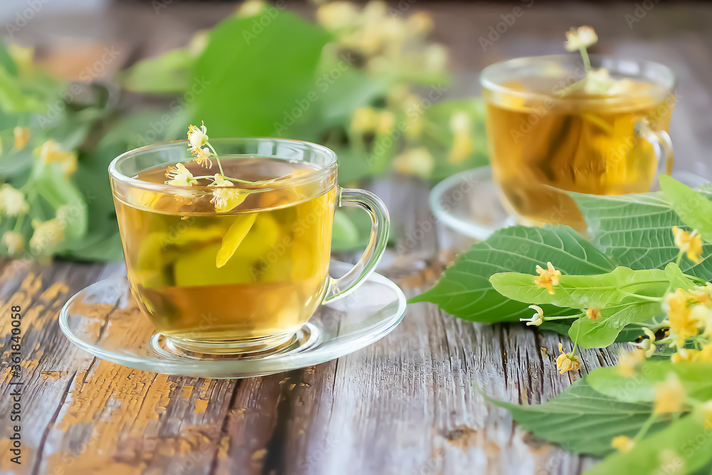 Herbal tea with linden inflorescences in glass cups on an old wooden table. Rustic style. Herbal tea with linden inflorescences in glass cups on an old wooden table. Rustic style.