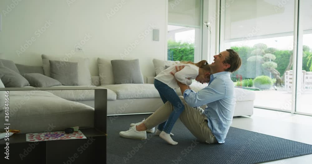 Authentic shot of carefree happy smiling father and daughter are having fun to play together on a floor just moved into a new house. Authentic shot of carefree happy smiling father and daughter are having fun to play together on a floor just moved into a new house.