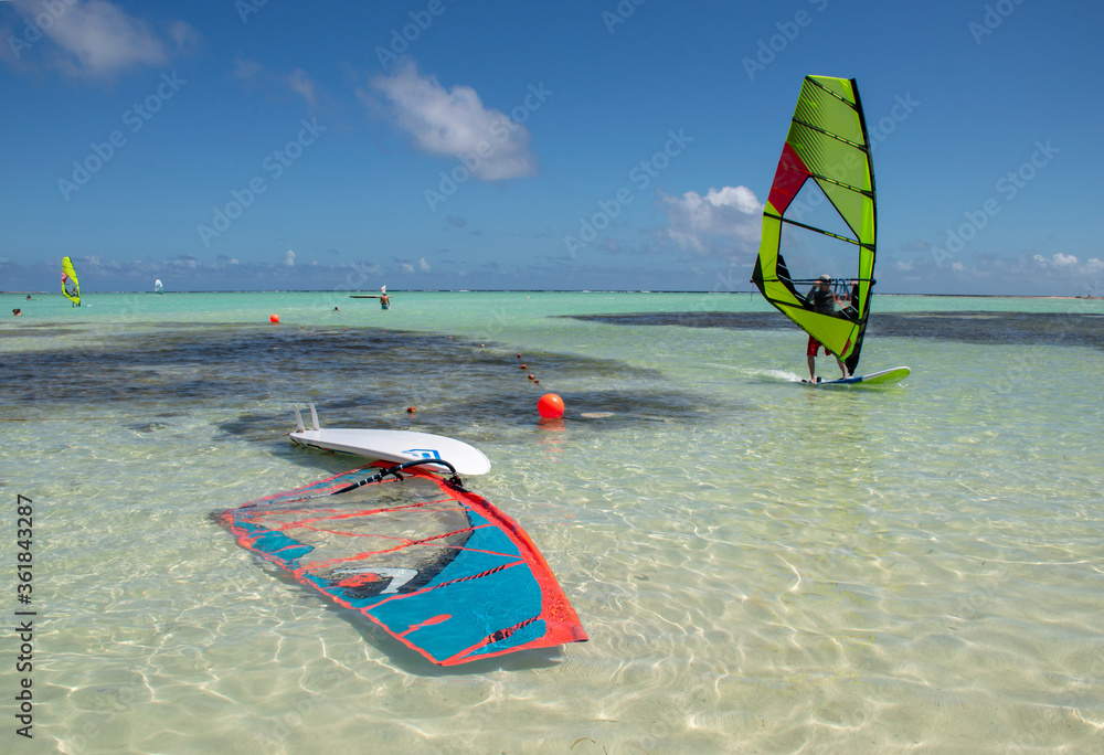 Surf board in the water and another surfer passing by on the turquoise water of Sorobon Beach in Bonaire Surf board in the water and another surfer passing by on the turquoise water of Sorobon Beach in Bonaire