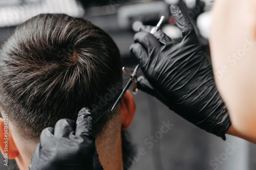 Woman barber cutting hair to a bearded man.
