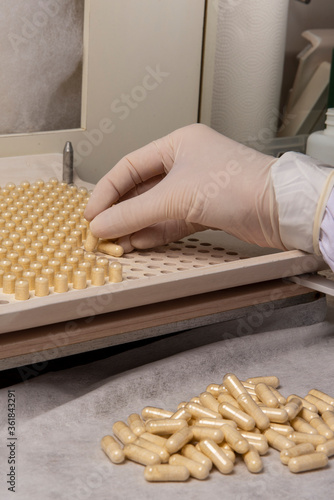 pharmacy professional using encapsulating plate for the production of homeopathic or allopathic remedies