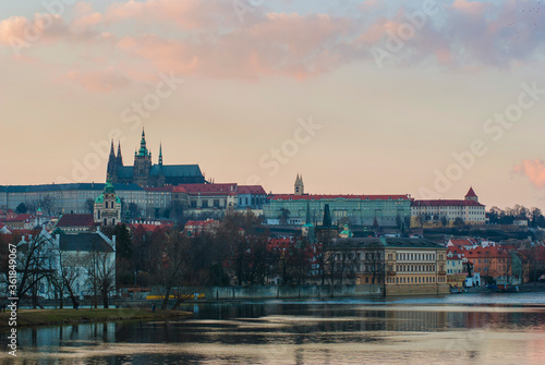 Panorama of Prague, Czech Republic at sunset. View of St. Vitus Cathedral from afar, buildings on the embankment of the Vltava River in the foreground.