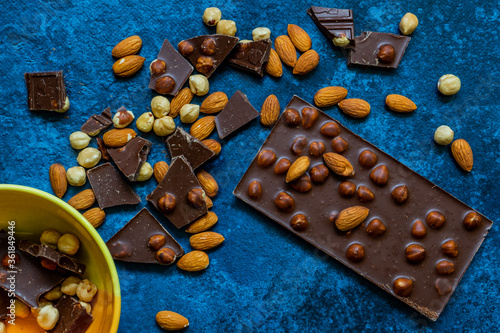 Chocolate chunks with hazelnuts isolated on blue background