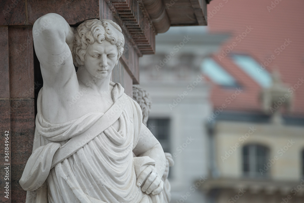 Obraz premium Statue of beautiful Roman noble man at the obelisk in the Old Market square (Alter Markt) in downtown of Potsdam, Germany