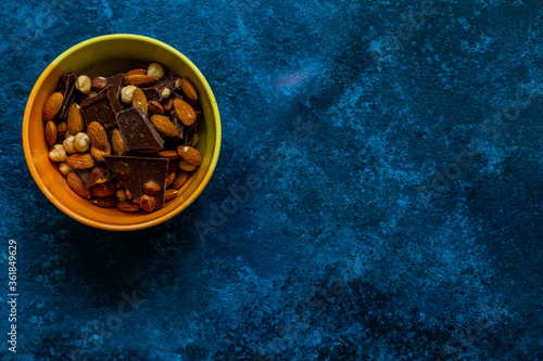 Chocolate chunks with hazelnuts isolated on blue background