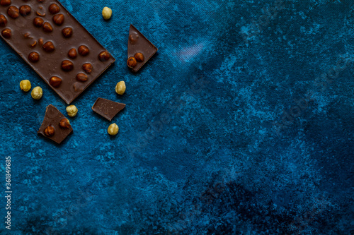 Chocolate chunks with hazelnuts isolated on blue background