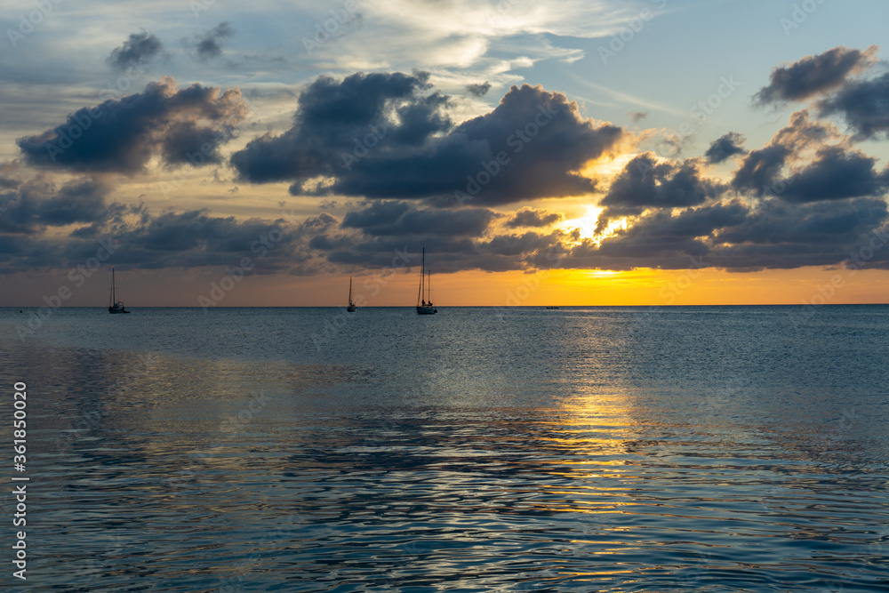 silhouettes of sail boats under a dark yellow and navy sunset silhouettes of sail boats under a dark yellow and navy sunset