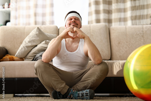 Guy sits at home carpet meditates and shows heart