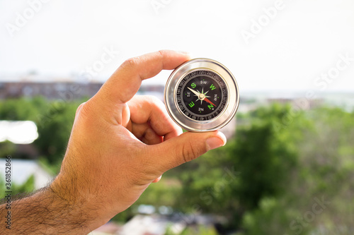 Holds compass against the background of nature