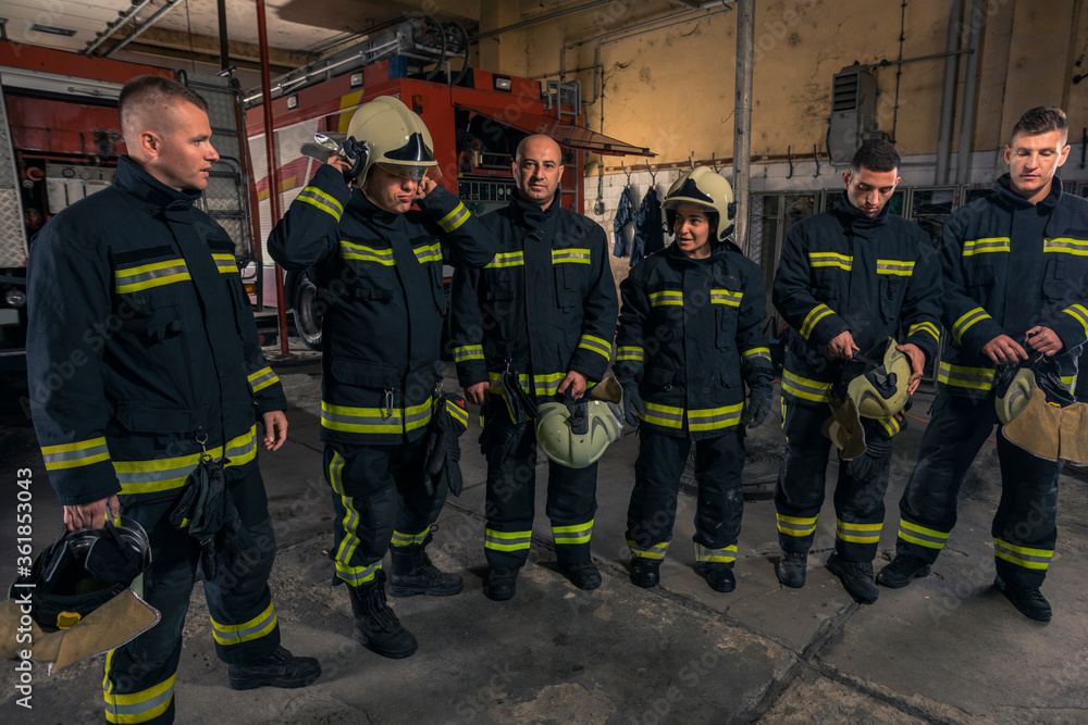Naklejka premium Portrait of firefighters standing by a fire engine.