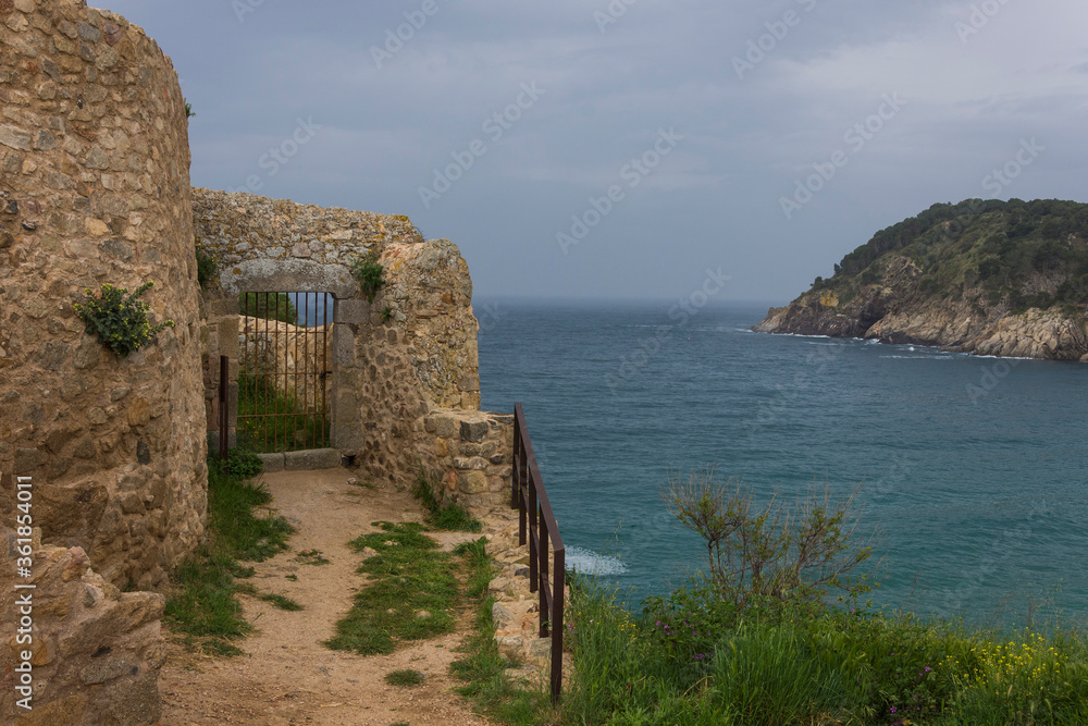 Stone building with gate with grating on the sea