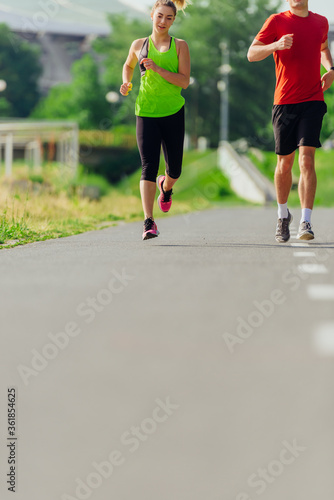 Young male and female athletes jogging and running on a road in the park.