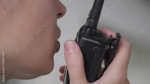 A woman in work clothes and a hard hat talking on a radio at a construction site