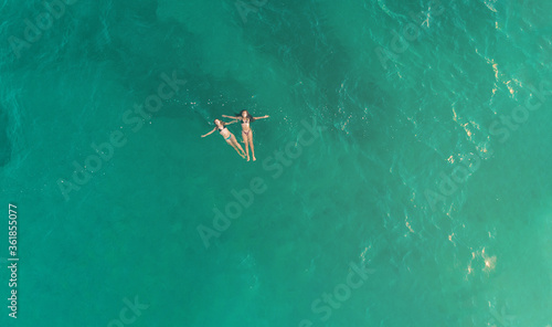 Aerial view of youngs girls in the blue sea in oaxaca mexico from above.