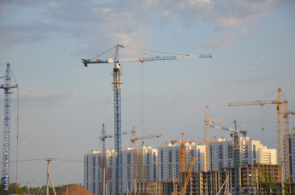 Inside place for many tall buildings under construction and cranes under a blue sky working on place with tall homes Inside place for many tall buildings under construction and cranes under a blue sky working on place with tall homes