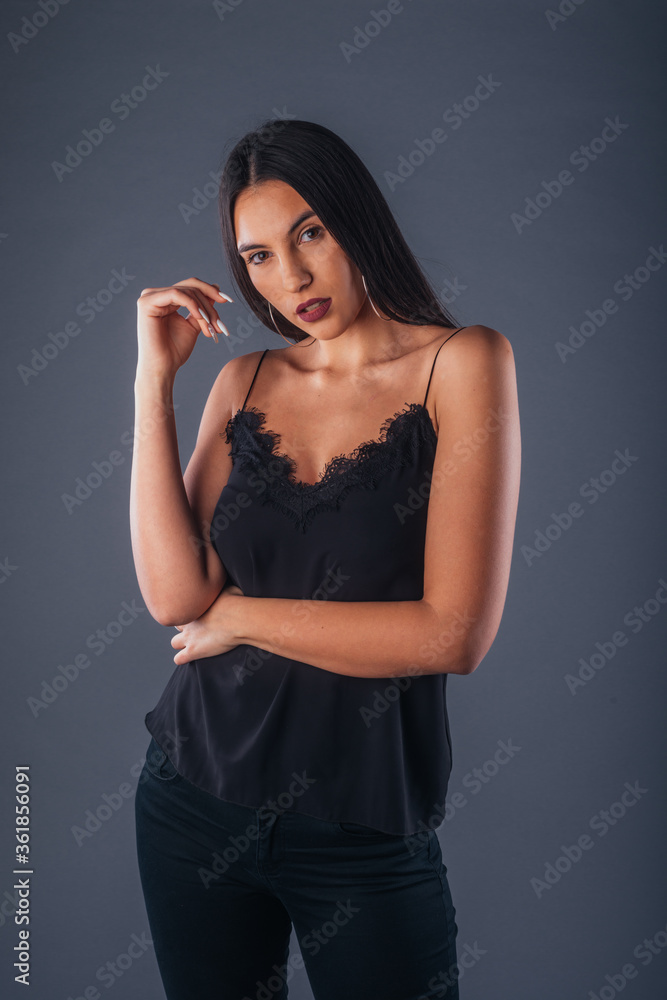 Sensual studio portrait of a sexy woman standing with one arm crossed on a gray background Sensual studio portrait of a sexy woman standing with one arm crossed on a gray background